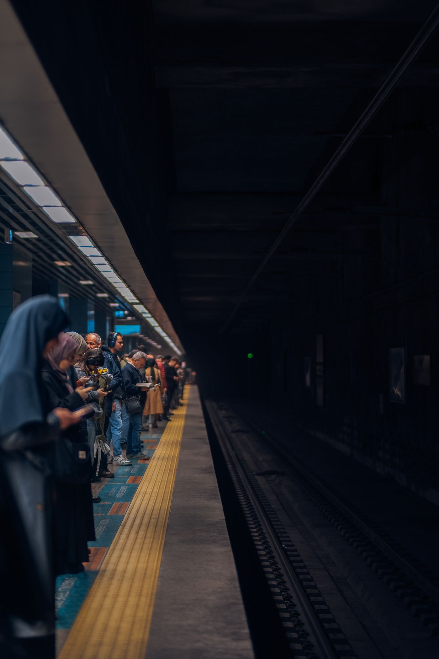 An underground metro platform with waiting commuters
