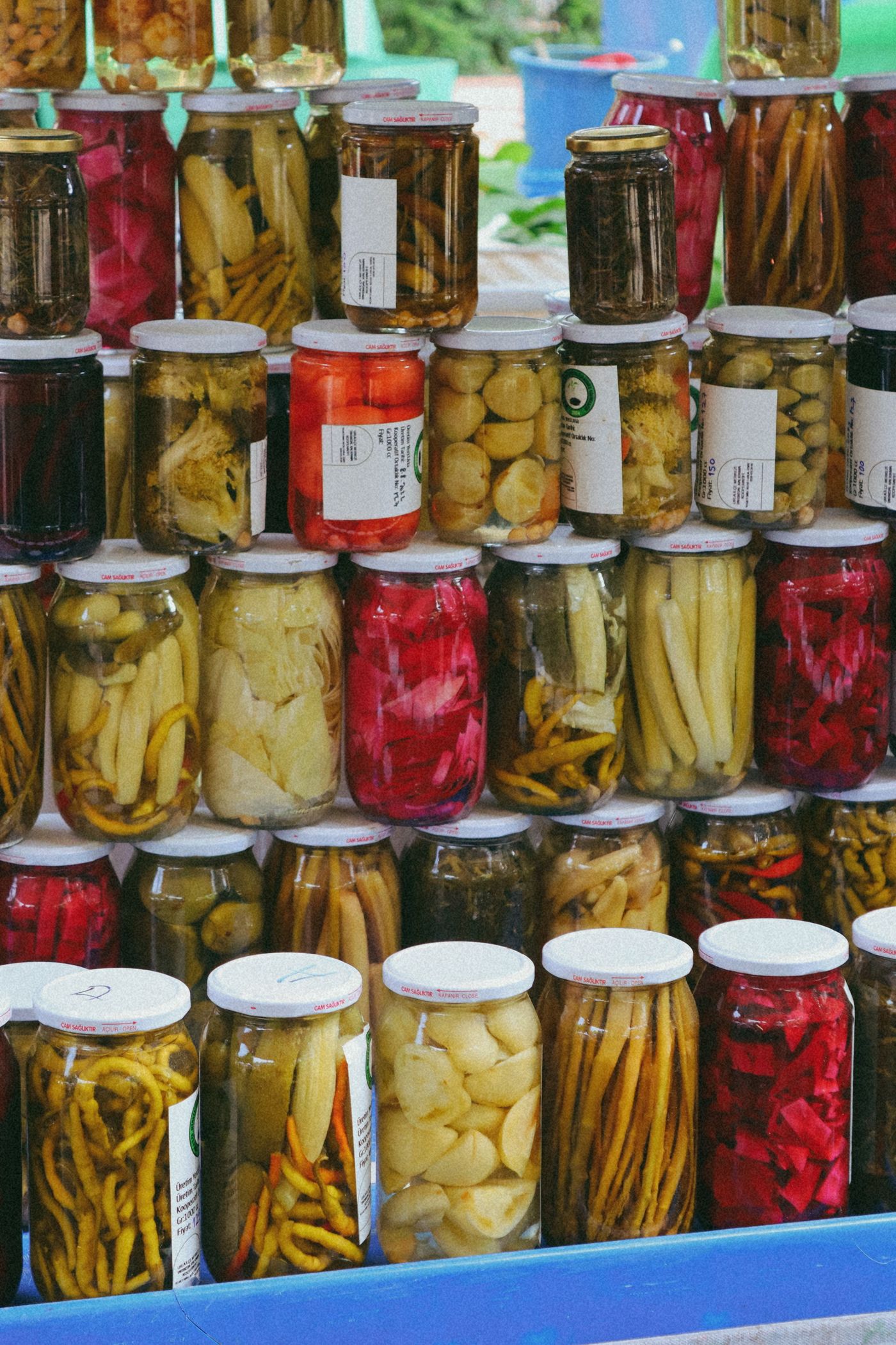 Stacked glass jars of Turkish pickles at a Kadıköy turşu shop, with pickled peppers, cucumbers, garlic, carrots and red cabbage